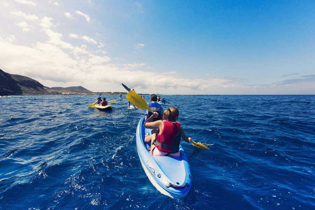 Menschen, die im Meer nahe der Küste von Teneriffa Kajak fahren.