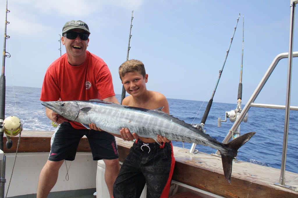Menschen, die einen großen Fisch auf einem Fischerboot auf Teneriffa halten.
