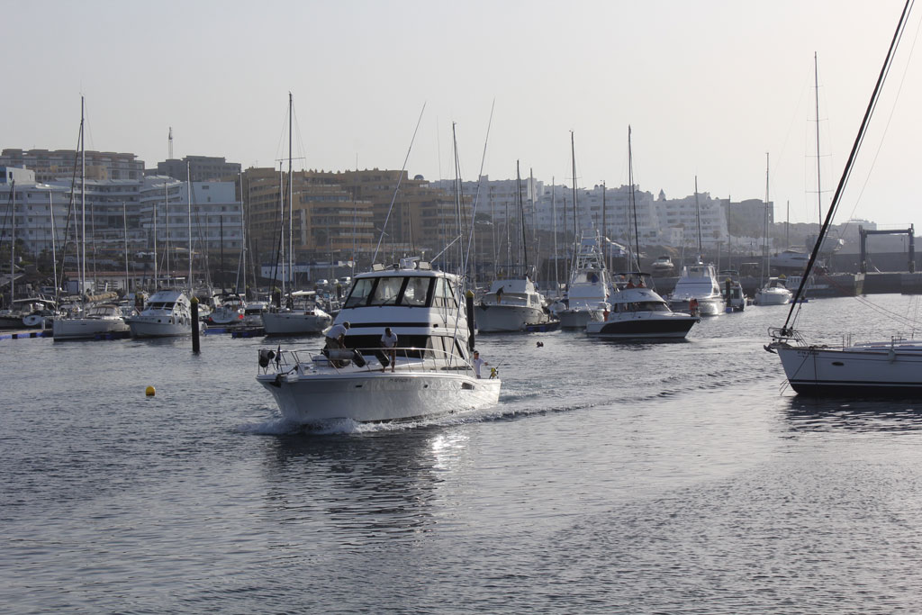 Boote im Hafen von Los Cristianos, Teneriffa, mit Gebäuden im Hintergrund.