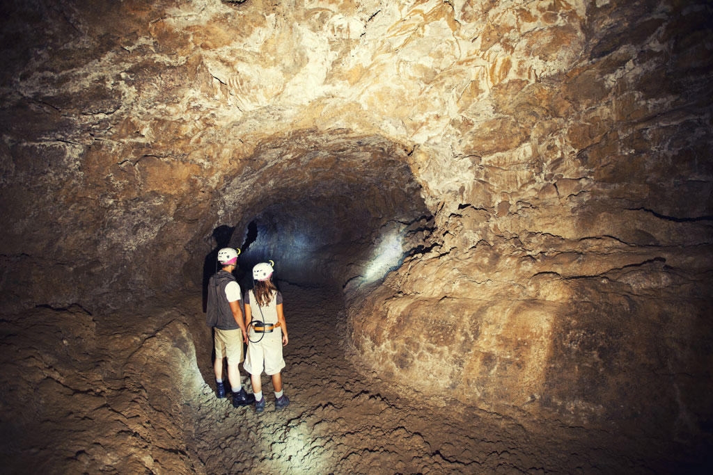 Entdecker mit Helmen gehen durch einen Tunnel in Cueva del Viento, Teneriffa.