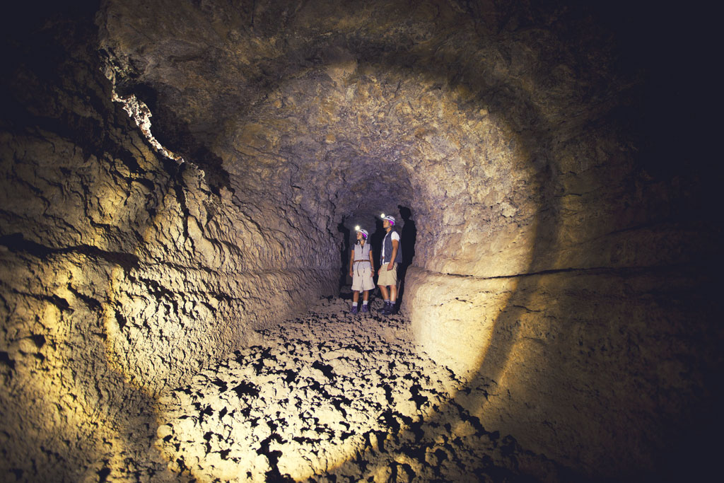 Entdecker mit Taschenlampen in einem vulkanischen Tunnel auf Teneriffa.