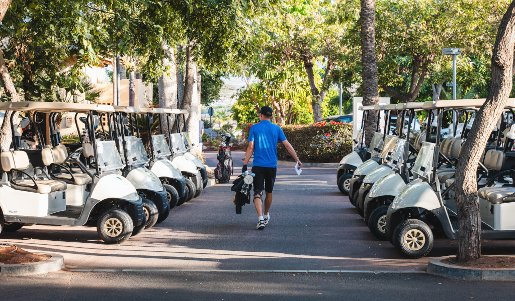 Der Mann läuft zwischen geparkten Golfwagen auf Teneriffa.