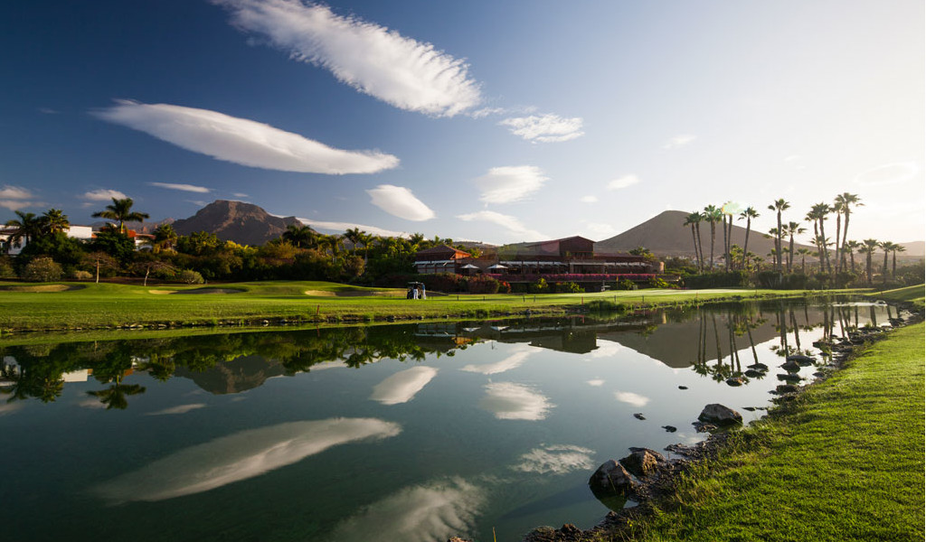 Golfplatz mit Bergen und Palmen, die sich in einem See auf Teneriffa spiegeln.