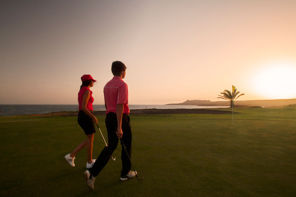 Menschen, die bei Sonnenuntergang an der Küste von Teneriffa Golf spielen.