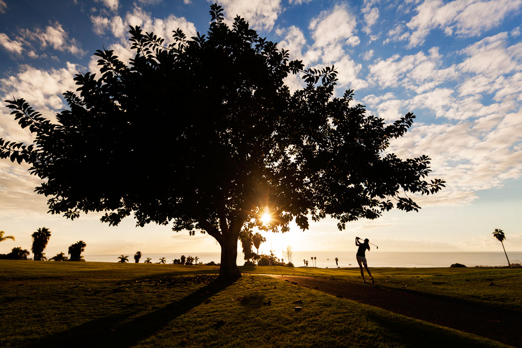 Person, die bei Sonnenuntergang auf einem Platz auf Teneriffa Golf spielt.