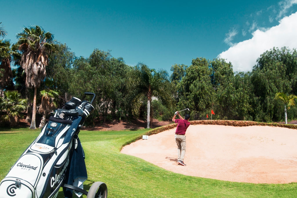 Golfer in Aktion auf einem Platz auf Teneriffa, in der Nähe eines Bunkers.