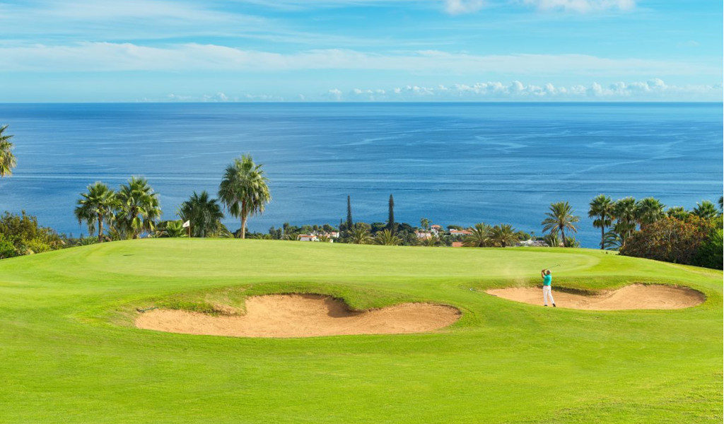 Golfplatz auf Teneriffa mit Meerblick. Schläge in der Nähe von Bunkern, die von Palmen umgeben sind.