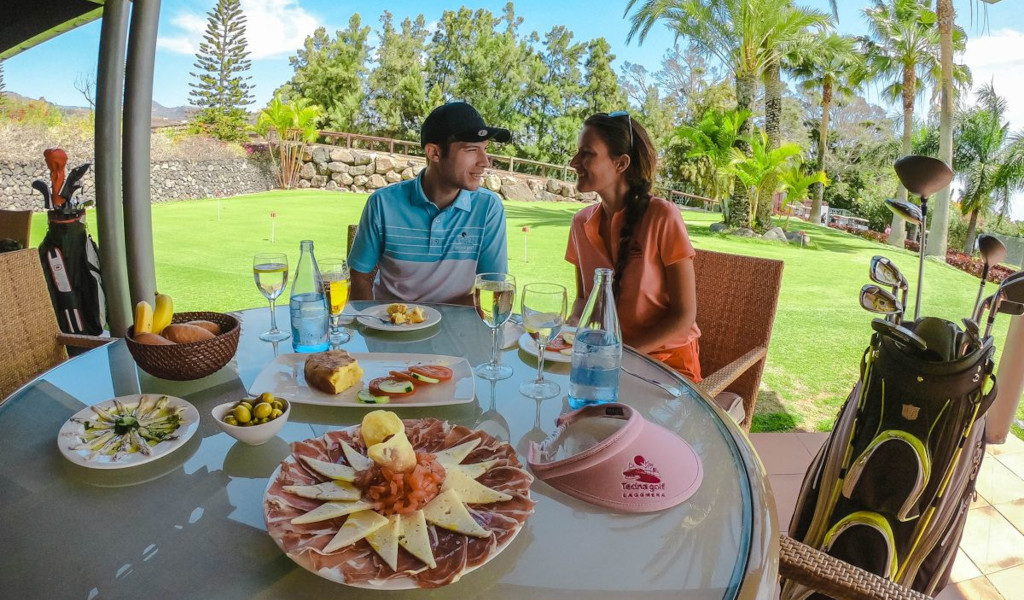 Ein Paar sitzt mit Essen und Golfschläger im Tecina Golf, La Gomera, Teneriffa.