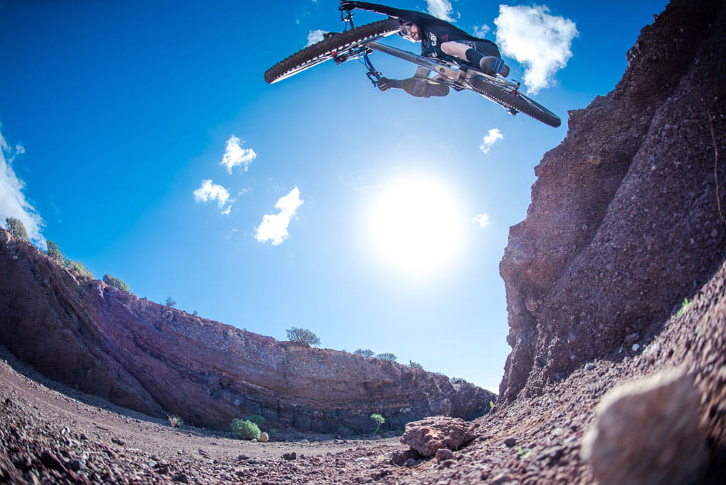 Radfahrer beim Extremsprung in einer Schlucht auf Teneriffa bei klarem Himmel.