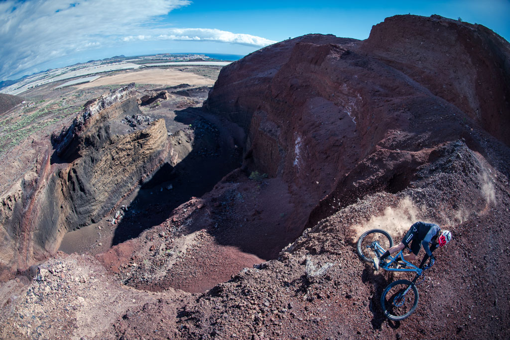 Radfahrer, der einen Hügel in einem Steinbruch auf Teneriffa hinabsteigt, mit Blick auf das Meer.