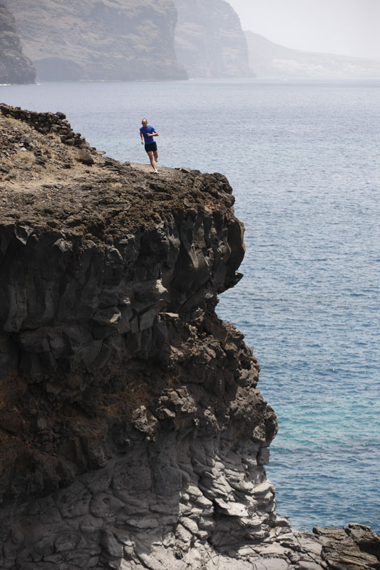 Person, die auf einer Klippe in Los Gigantes, Teneriffa, läuft, mit dem Meer im Hintergrund.