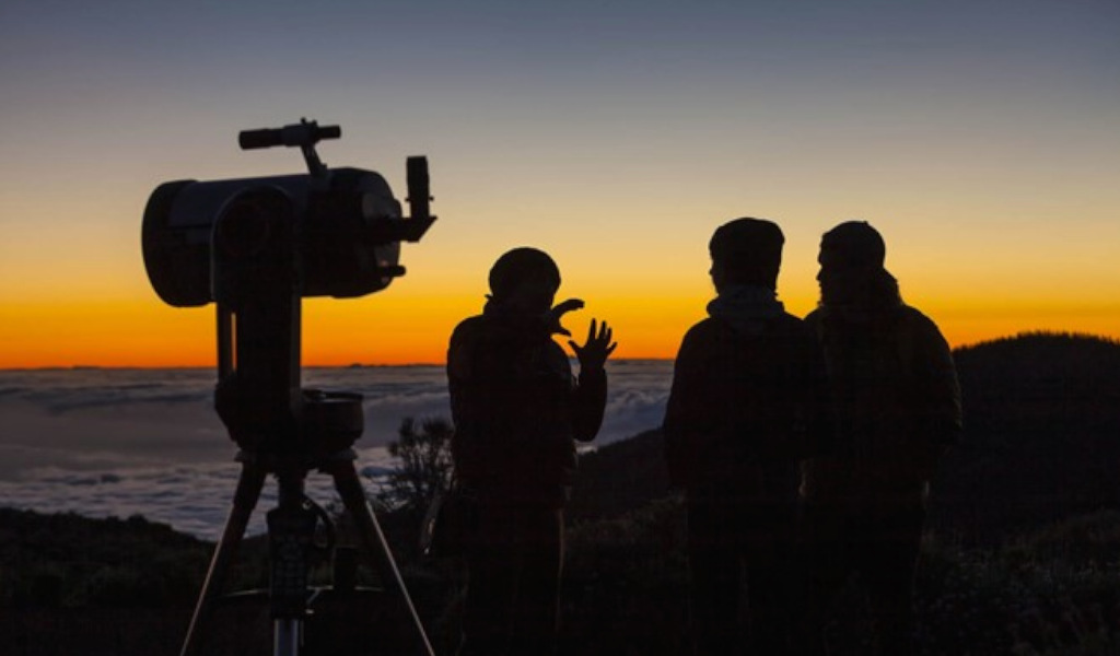 Menschen, die den Sonnenaufgang mit einem Teleskop auf Teneriffa beobachten.