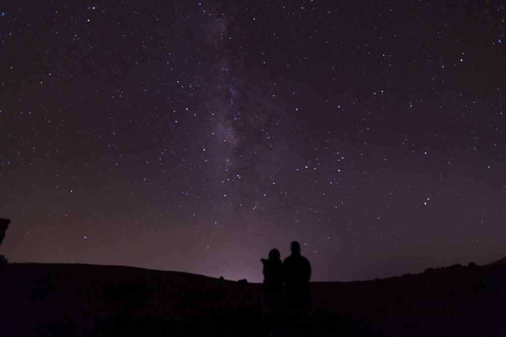 Sternenhimmel über dem Teide auf Teneriffa, mit zwei Silhouetten, die zusehen.