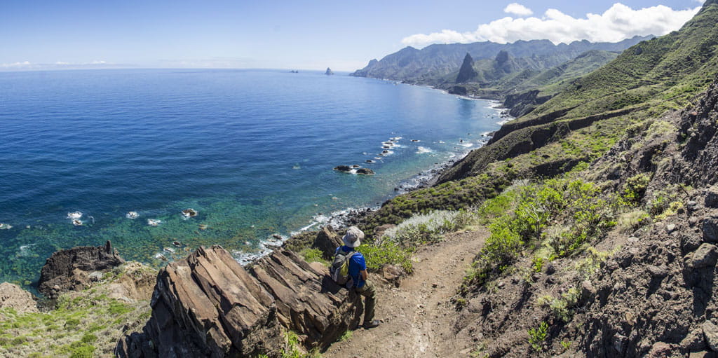 Person, die entlang eines Küstenpfades in Anaga, Teneriffa, mit Blick auf den Ozean spaziert.