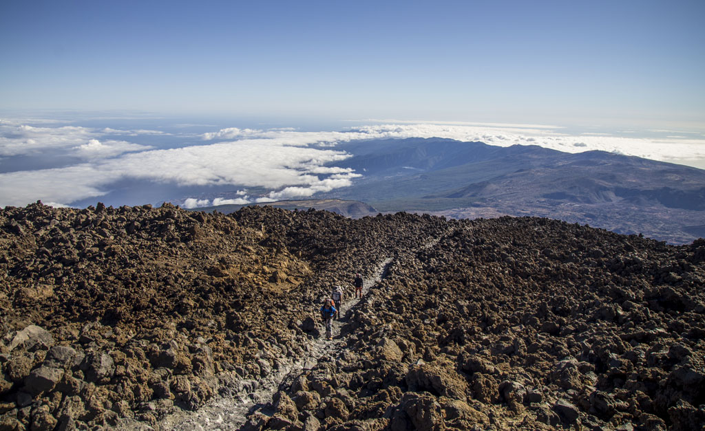 Wanderer auf dem Teide-Pfad, Teneriffa, mit Wolken und Bergen im Hintergrund.