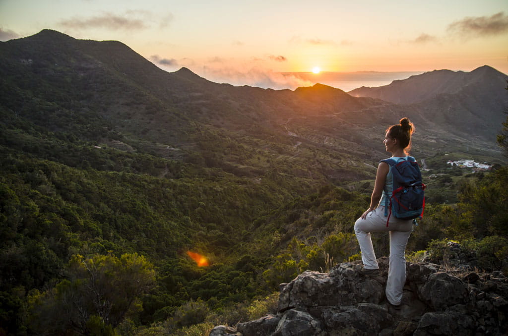 Die Person mit Rucksack beobachtet den Sonnenuntergang von einem Aussichtspunkt in den Bergen von Teneriffa.