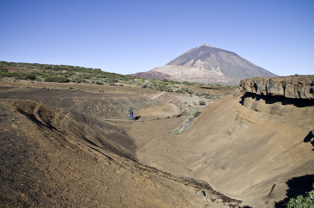 Person, die unter klarem Himmel in der Nähe des Teide-Vulkans auf Teneriffa spaziert.