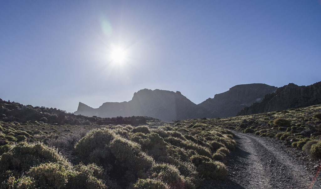 Bergiger Wanderweg im Nationalpark Teide, Teneriffa, mit der Sonne am Horizont.
