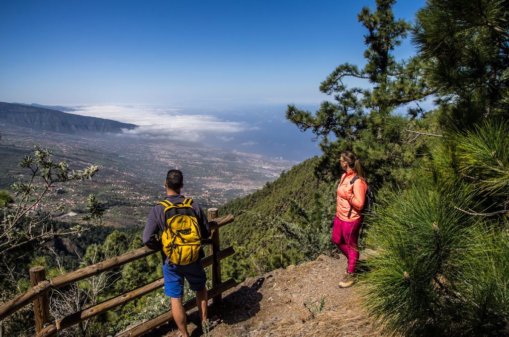Zwei Personen mit Rucksäcken beobachten die Landschaft von einem Aussichtspunkt auf Teneriffa.