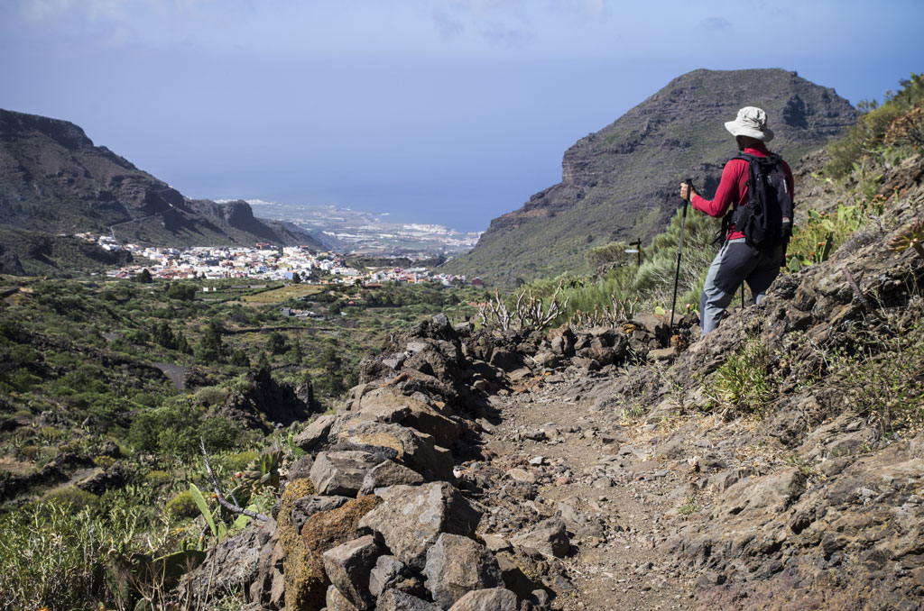 Wanderer mit Stöcken auf einem bergigen Weg, Blick auf Masca, Teneriffa.