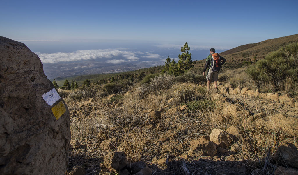 Wanderer auf einem bergigen Weg auf Teneriffa mit Meeresblick und klarem Himmel.