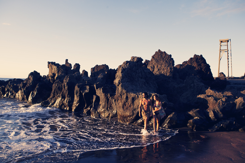 Menschen, die am Strand entlang neben Felsen in Bajamar, Teneriffa, spazieren gehen.