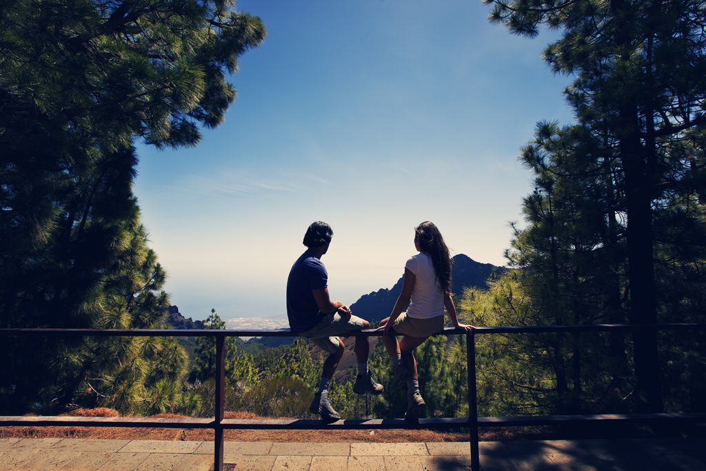Zwei Personen sitzen auf einem Aussichtspunkt mit Blick auf das Meer auf Teneriffa.