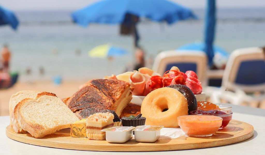 Abwechslungsreiches Frühstück am Strand von Las Teresitas, Teneriffa, mit Toast und Obst.