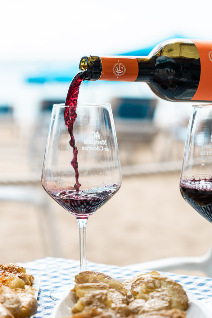 Rotwein wurde in ein Glas mit Kuchen auf einem Strandtisch auf Teneriffa gegossen.