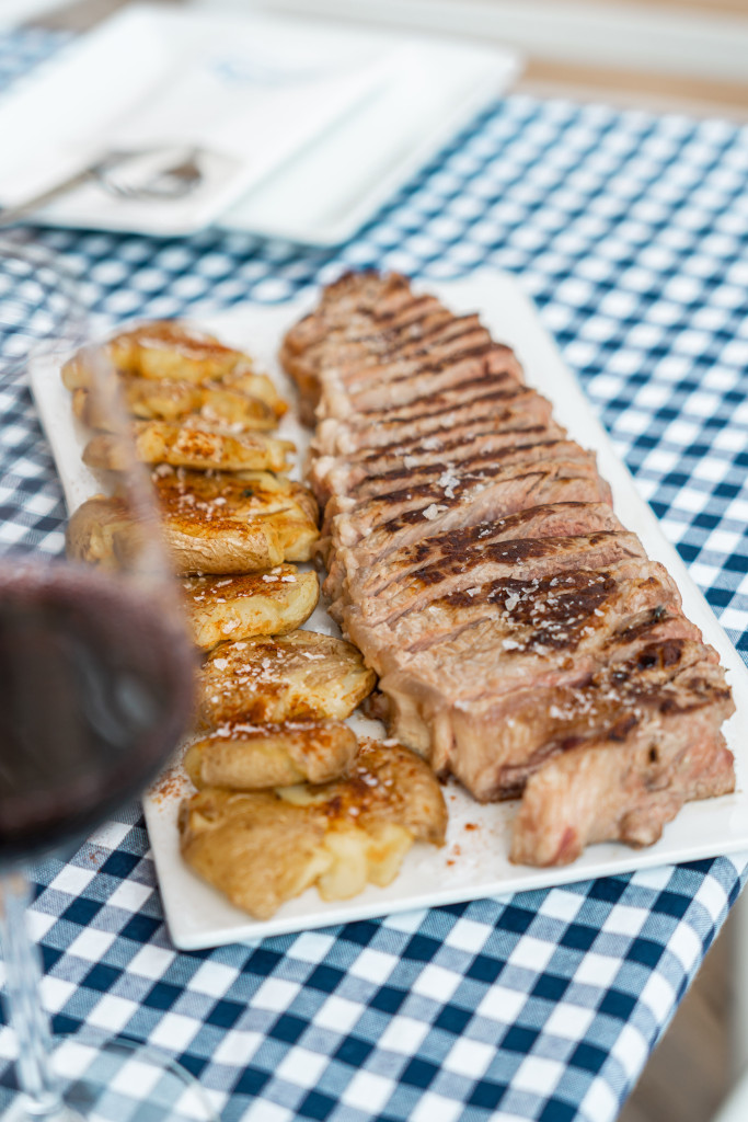 Gegrilltes Fleisch mit Kartoffeln auf einem Teller auf einer karierten Tischdecke auf Teneriffa.