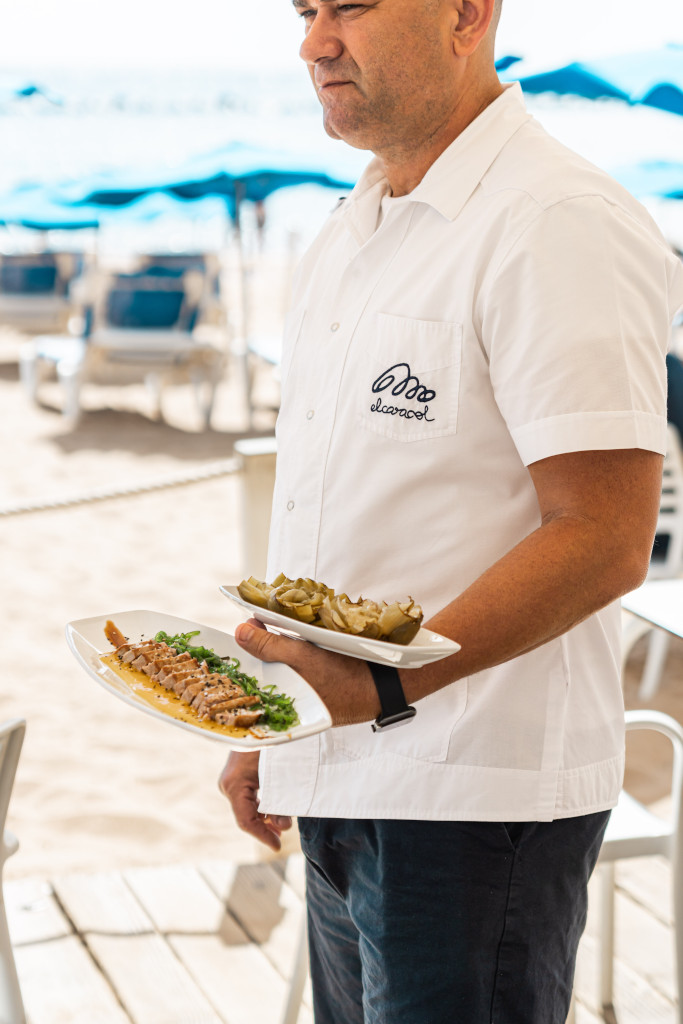 Person, die Teller mit Essen an einem Strand auf Teneriffa serviert.