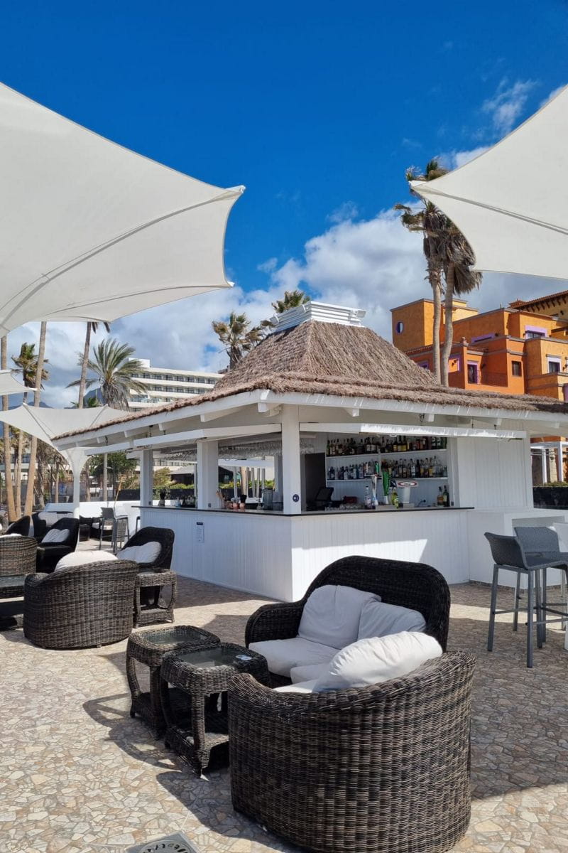 Open-Air-Bar mit Strohdach, Tischen und Stühlen auf Teneriffa.