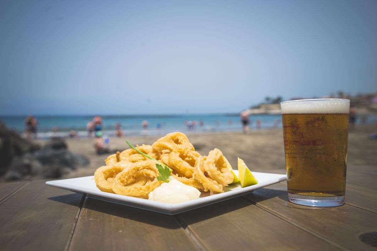 Frittierter Tintenfisch mit Zitrone und Bier am Strand von Adeje, Teneriffa.