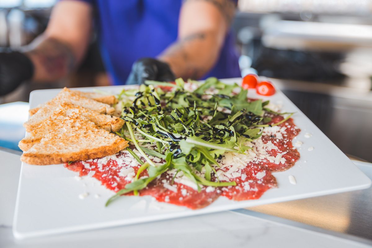 Rindcarpaccio mit Rucola und getoastetem Brot in einem Restaurant auf Teneriffa.