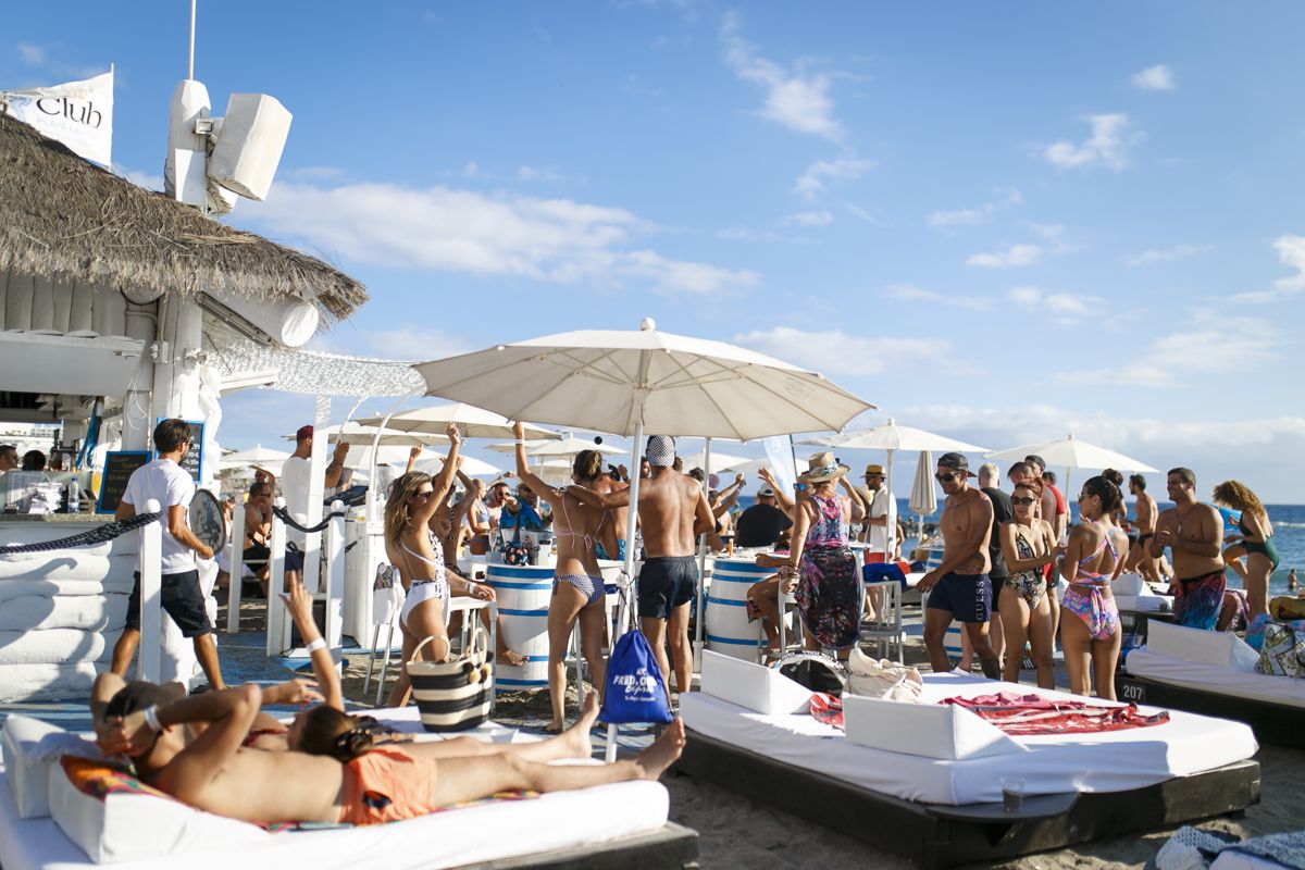 Menschen, die einen Strandclub auf Teneriffa unter Schirmen genießen.