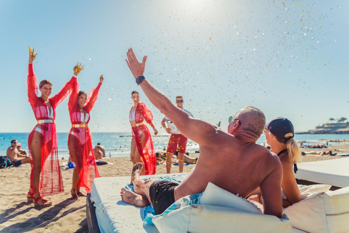 Menschen, die den Strand mit Tänzern in Puerto de la Cruz, Teneriffa, genießen.