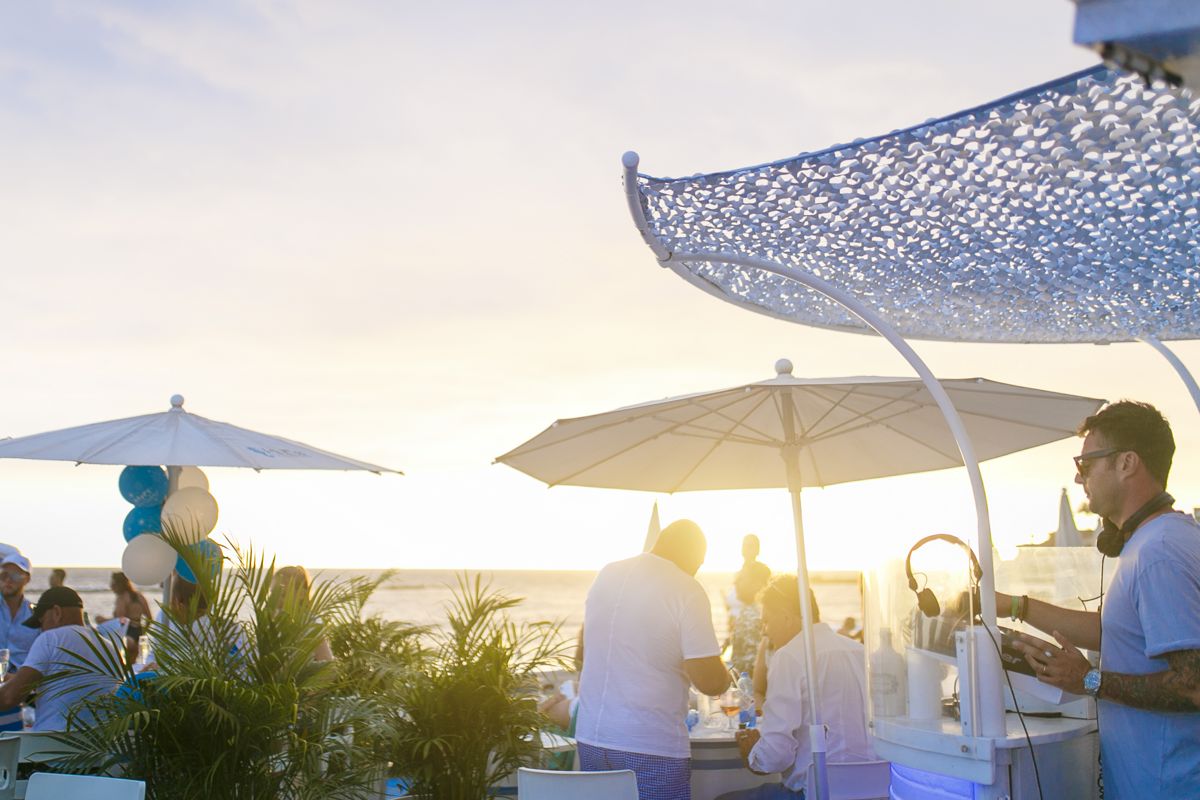 Menschen, die sich auf einer Terrasse am Meer auf Teneriffa bei Sonnenuntergang amüsieren.