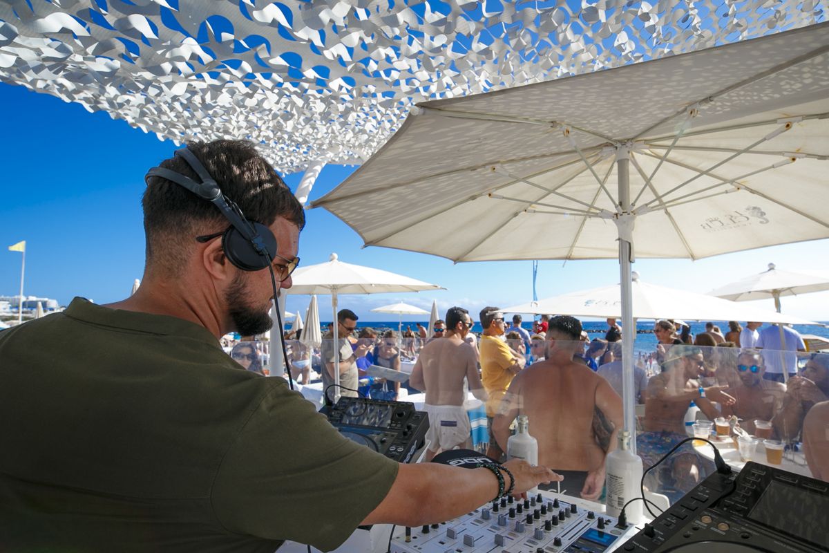DJ bei einer Open-Air-Veranstaltung am Strand von Teneriffa, mit einem Publikum, das sich amüsiert.