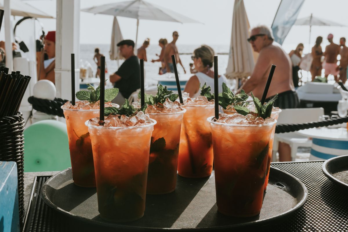Gläser Cocktails mit Minze und Eis an einem belebten Strand auf Teneriffa.