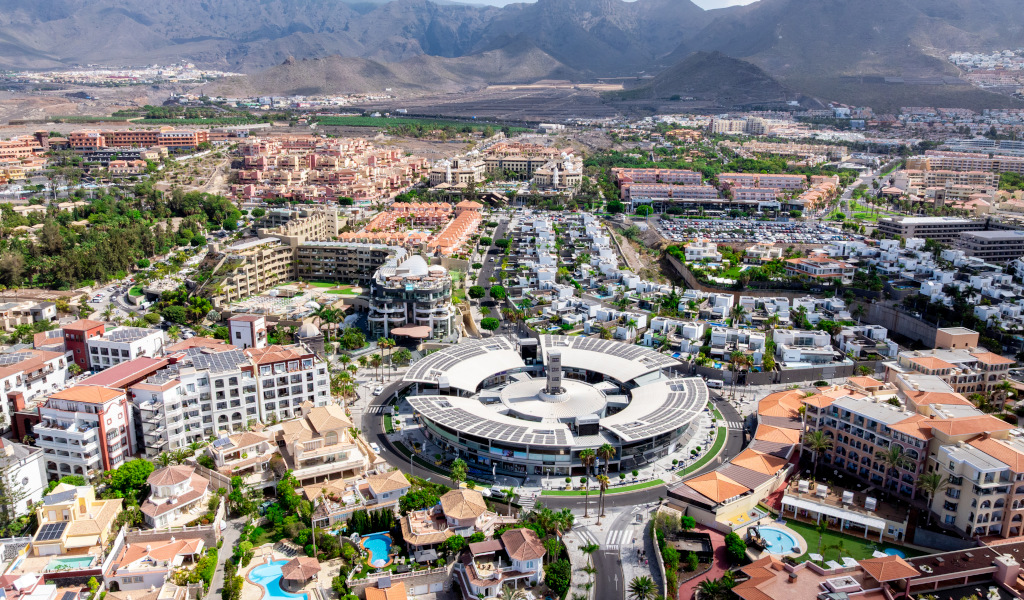 Luftaufnahme der Costa Adeje auf Teneriffa mit Gebäuden und Bergen im Hintergrund.