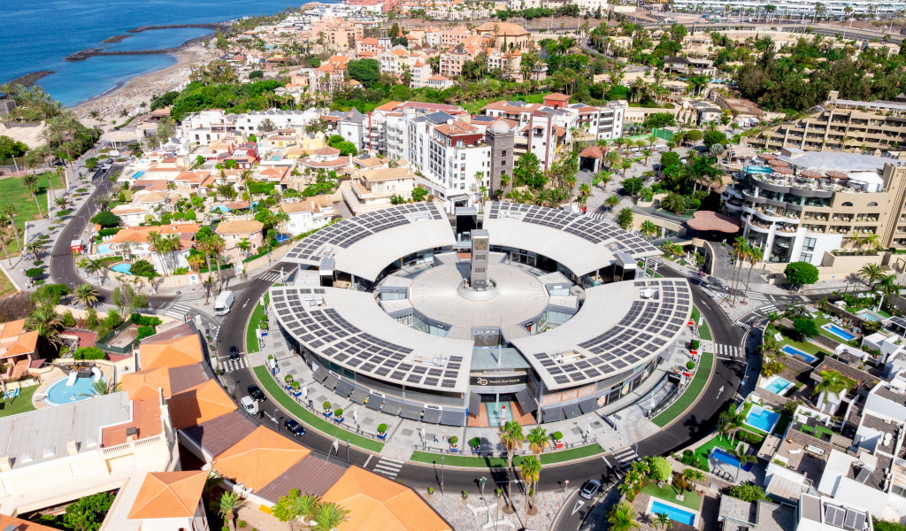 Luftaufnahme des Einkaufszentrums Plaza del Duque auf Teneriffa, umgeben von Gebäuden und dem Meer.
