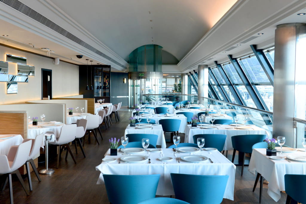 Eleganter Speisesaal mit Tischen, die in einem Restaurant mit Blick nach außen auf Teneriffa vorbereitet wurden.
