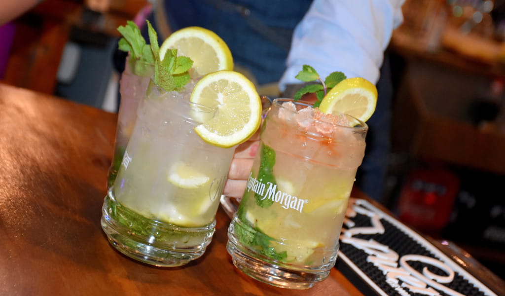 Zwei Cocktails mit Zitronen- und Minzscheiben in Captain Morgan-Gläsern in einer Bar auf Teneriffa.
