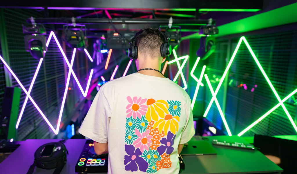 DJ in einem floralen T-Shirt mischt Musik im Club auf Teneriffa mit Neonlichtern.