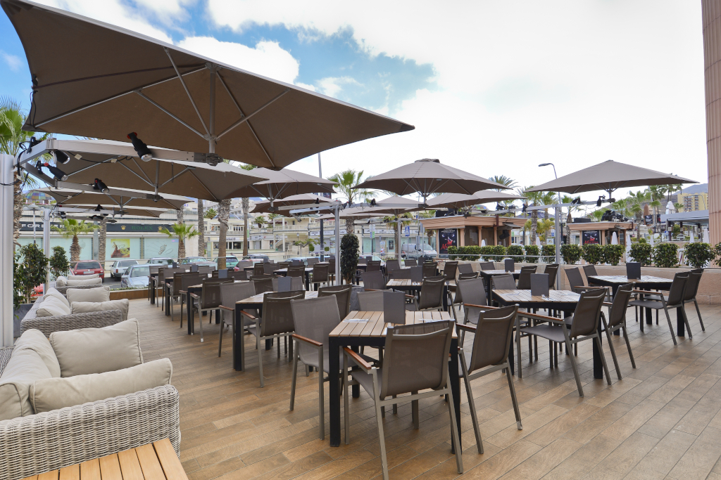Terrasse mit Tischen und Stühlen unter Sonnenschirmen im Einkaufszentrum von Teneriffa.