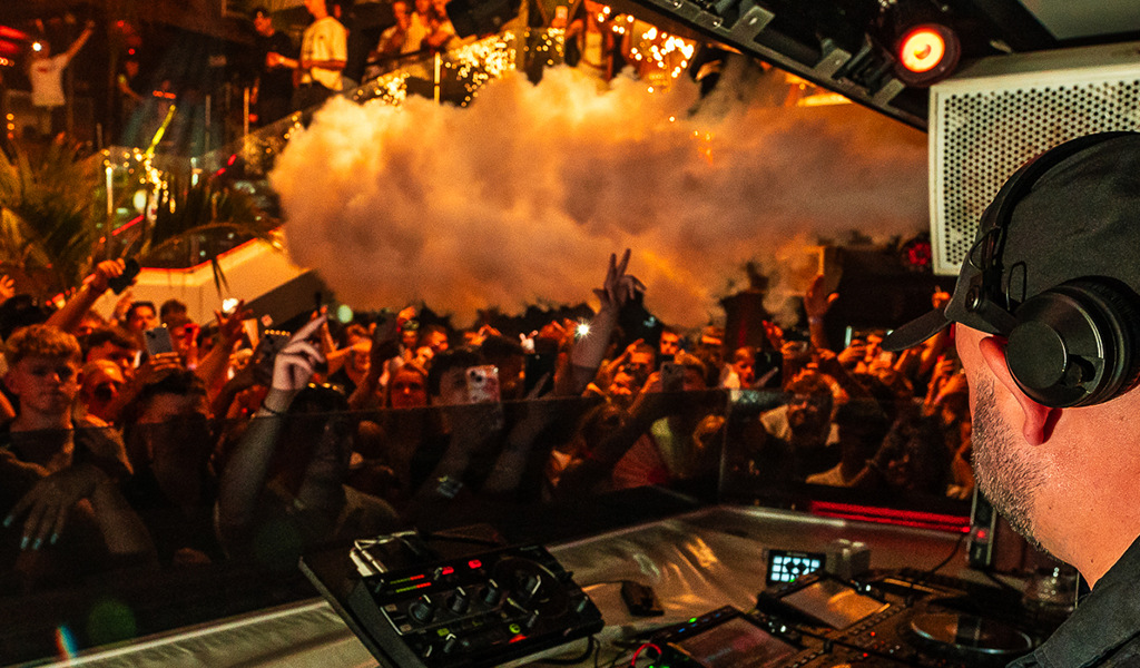 DJ, der live vor einem lebhaften Publikum in einem Club auf Teneriffa spielt.