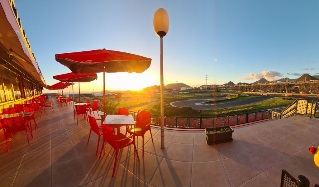 Restaurantterrasse mit roten Tischen und Blick auf den Sonnenuntergang auf einer Runde auf Teneriffa.