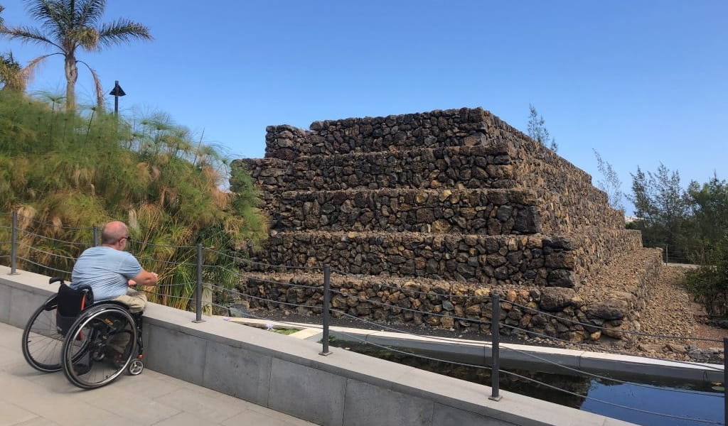 Person im Rollstuhl, die eine Pyramide in Güímar, Teneriffa, betrachtet.