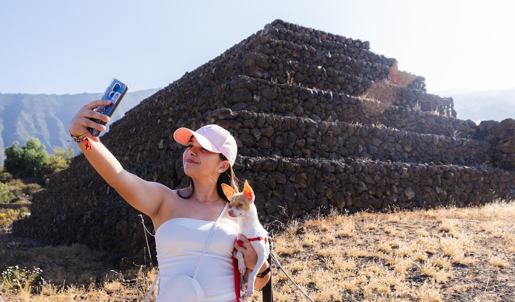 Person, die ein Selfie mit einem Hund vor den Pyramiden von Güímar auf Teneriffa macht.