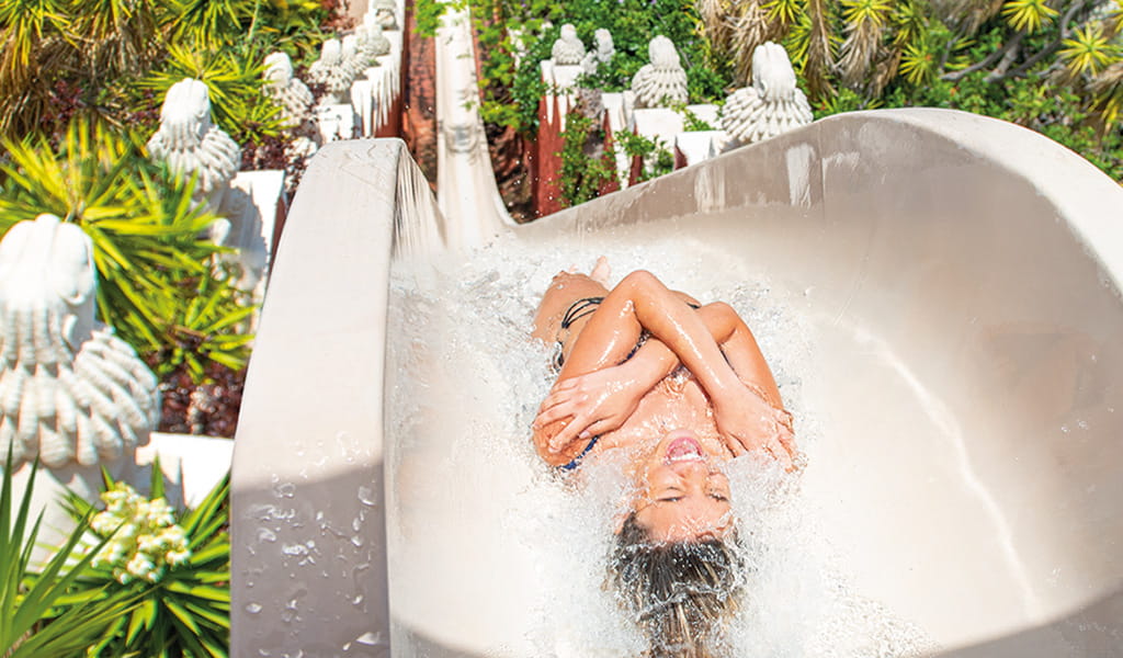 Person, die im Siam-Park, Teneriffa, eine Wasserrutsche hinunterrutscht.